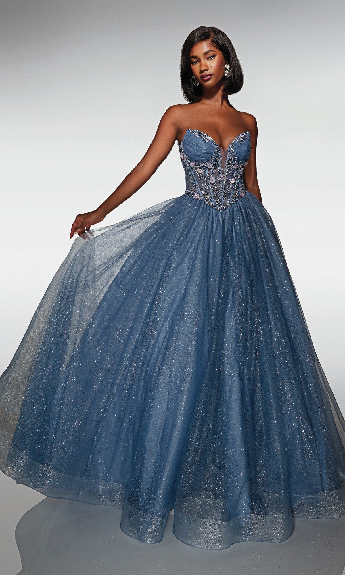 A woman models the Alyce 62009 long prom dress in Dark French Blue, a strapless glitter tulle ball gown with a fitted corset bodice and a full sparkling skirt, posing against a plain background.